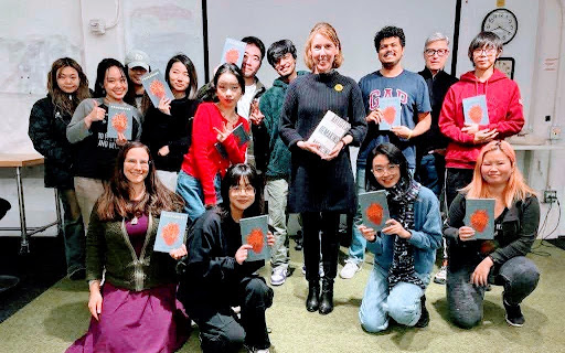 Emily holding a copy of Artists Remaking Medicine